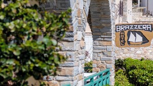 A stone archway leading to a building with a sign for 'Brazzeria Hotel.'