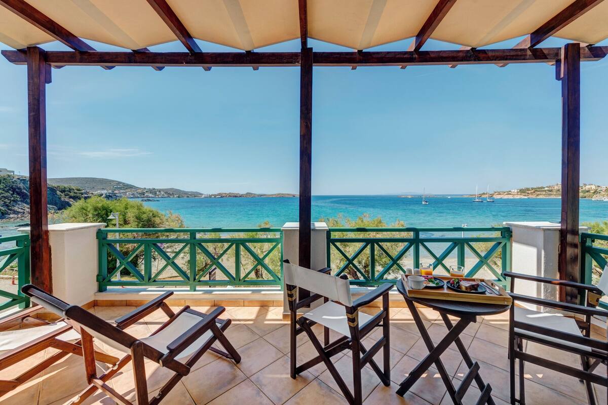 A covered outdoor seating area with a view of the sea.