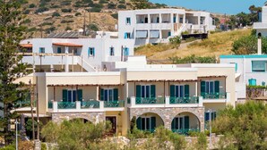 A coastal building with multiple balconies, a stone archway, and a view of the sea.