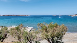 A coastal landscape with clear blue sea, boats, and sparse vegetation.