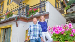 A hotel entrance with a yellow facade, a staircase, and balconies with flower boxes. - Hotel Meublè Sertorelli Reit (Bormio)