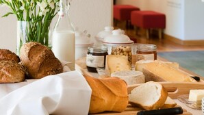 A breakfast buffet with various breads, cheeses, and a vase of flowers. - Hotel Meublè Sertorelli Reit (Bormio)