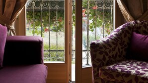 A room with a large window, a purple sofa, and a glass table. - Hotel Meublè Sertorelli Reit (Bormio)