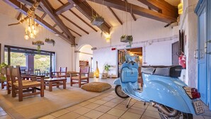 Una habitación con muebles de madera, un scooter azul y plantas colgantes.