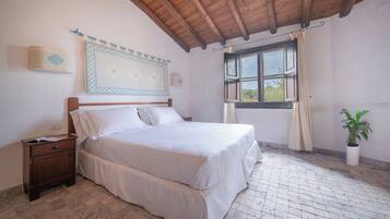 A bedroom with a wooden ceiling, a bed with white bedding, a nightstand, a window with curtains, and a potted plant.