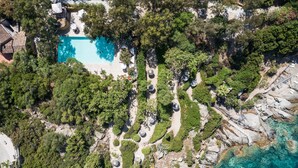 Vista aérea de un resort con piscina rodeada de exuberante follaje y terreno rocoso.