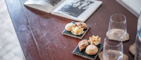 A wooden table with a book, two small plates with pastries, and a glass of water.