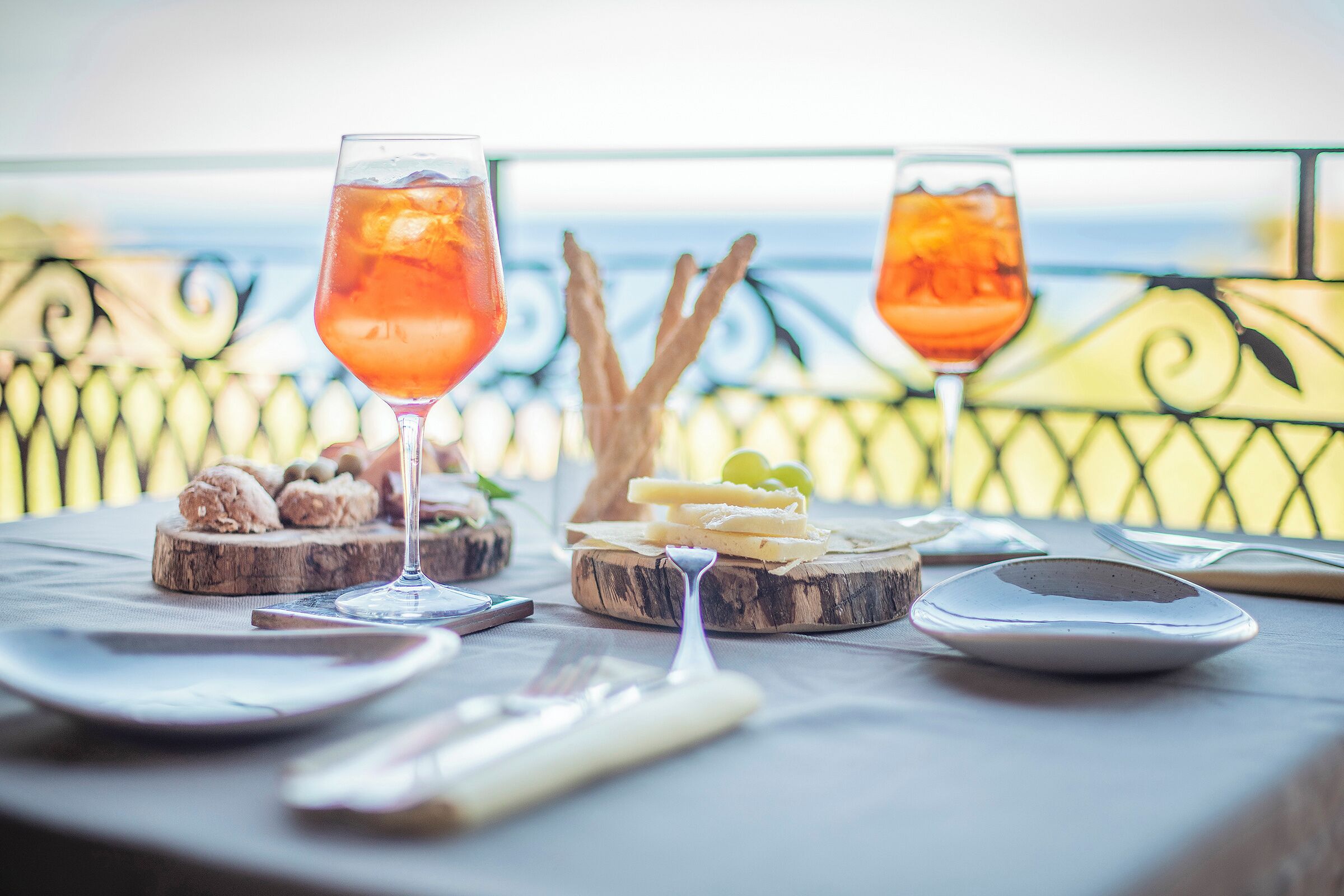A table with two glasses of a pink beverage, cheese, and crackers on a wooden board.