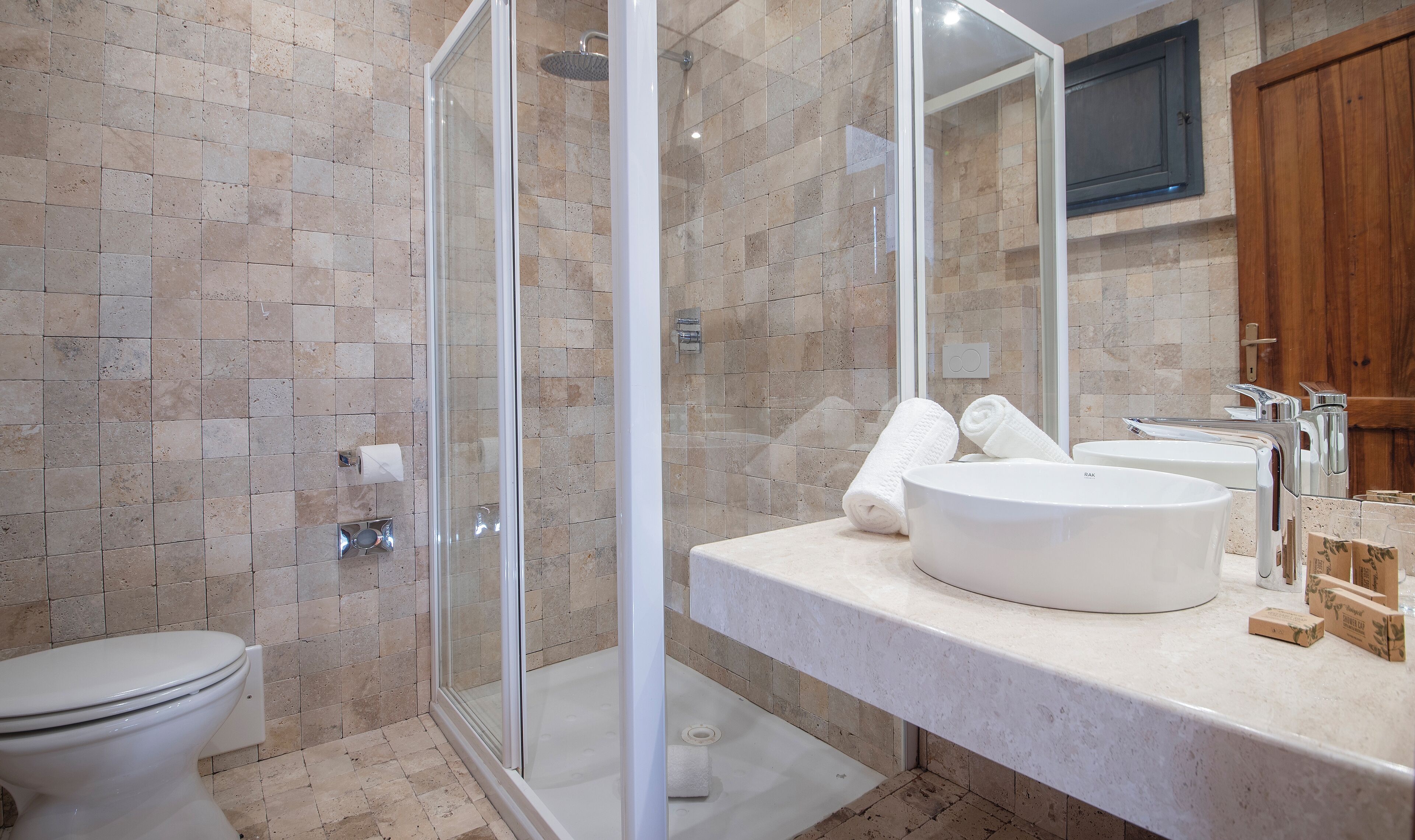 Un baño moderno con ducha de vidrio, inodoro y tocador doble con espejo.