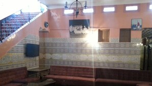 Una sala de estar con una escalera, papel tapiz estampado y alfombra roja.