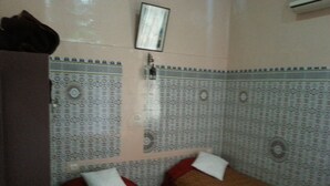 Una habitación con dos camas, paredes decoradas, una mesita pequeña y un aire acondicionado instalado en la pared.