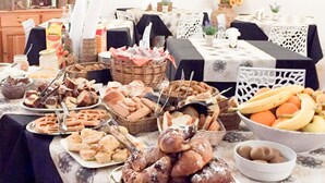 A dining table with various food items, a television on the wall, and a cabinet in the background. - Hotel Il Cortile (Custonaci)