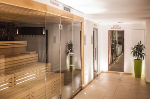 Uma área de spa moderna com bancos de madeira, divisória de vidro e um vaso com planta.