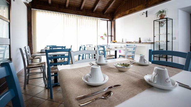 A dining area with a table set for two, featuring white plates and cups, and a buffet table in the background. - Cabrera House (Pozzallo)