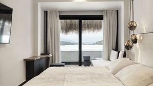 Un dormitorio moderno con una cama grande, una mesita de noche, vistas al mar y una lámpara colgante.