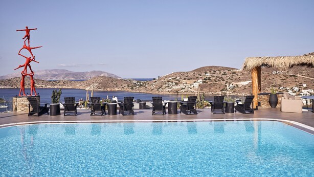 Una piscina con sillas de descanso y vistas al mar y colinas.