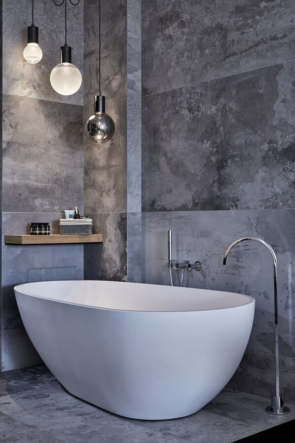 A modern bathroom with a freestanding bathtub, a minimalist sink, and a shower with a chrome faucet. - Liostasi (Ios)