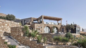 Un edificio de piedra con escaleras, ventanas arqueadas y una estructura de techo de paja.