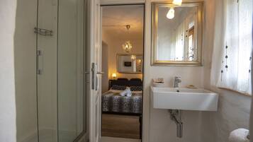 Habitación de hotel con armario de puerta de cristal, cama con colcha de estampado de leopardo, lavabo blanco y espejo encima.