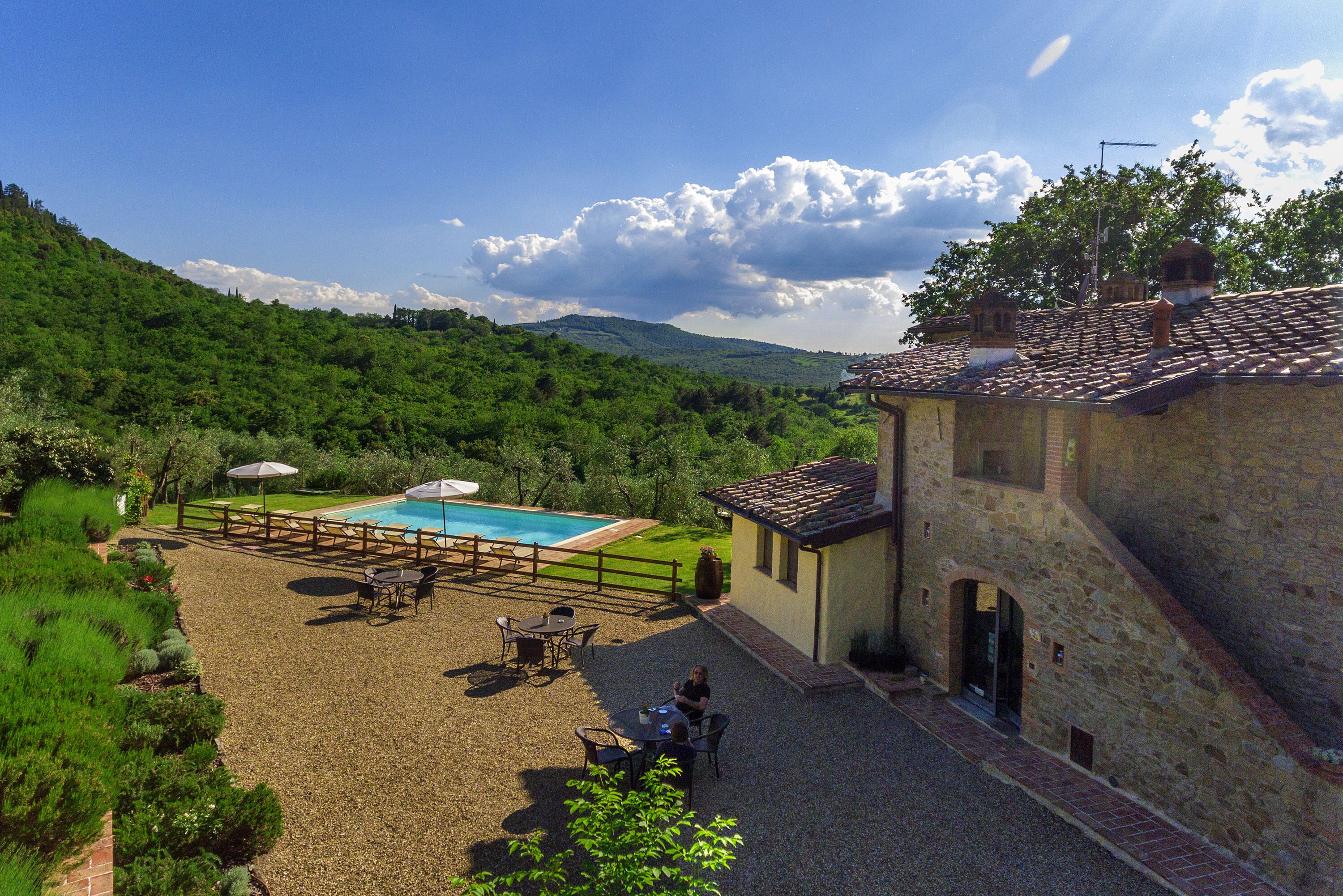 Una villa con piscina, zona de estar exterior y vistas de las colinas circundantes.