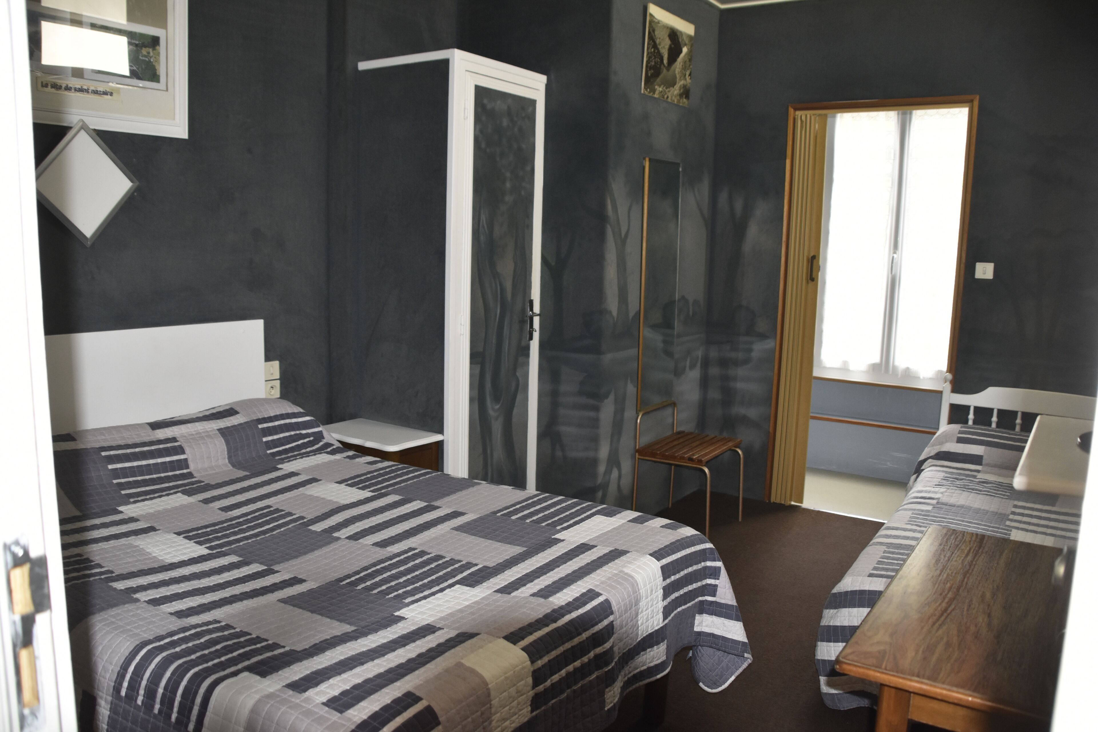 Un dormitorio con una cama, una mesa de madera, una silla y un armario.