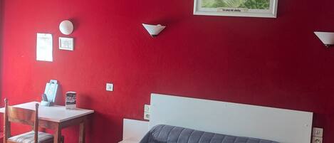 Une chambre d’hôtel avec un lit, un bureau, une chaise et un tableau accroché au mur.