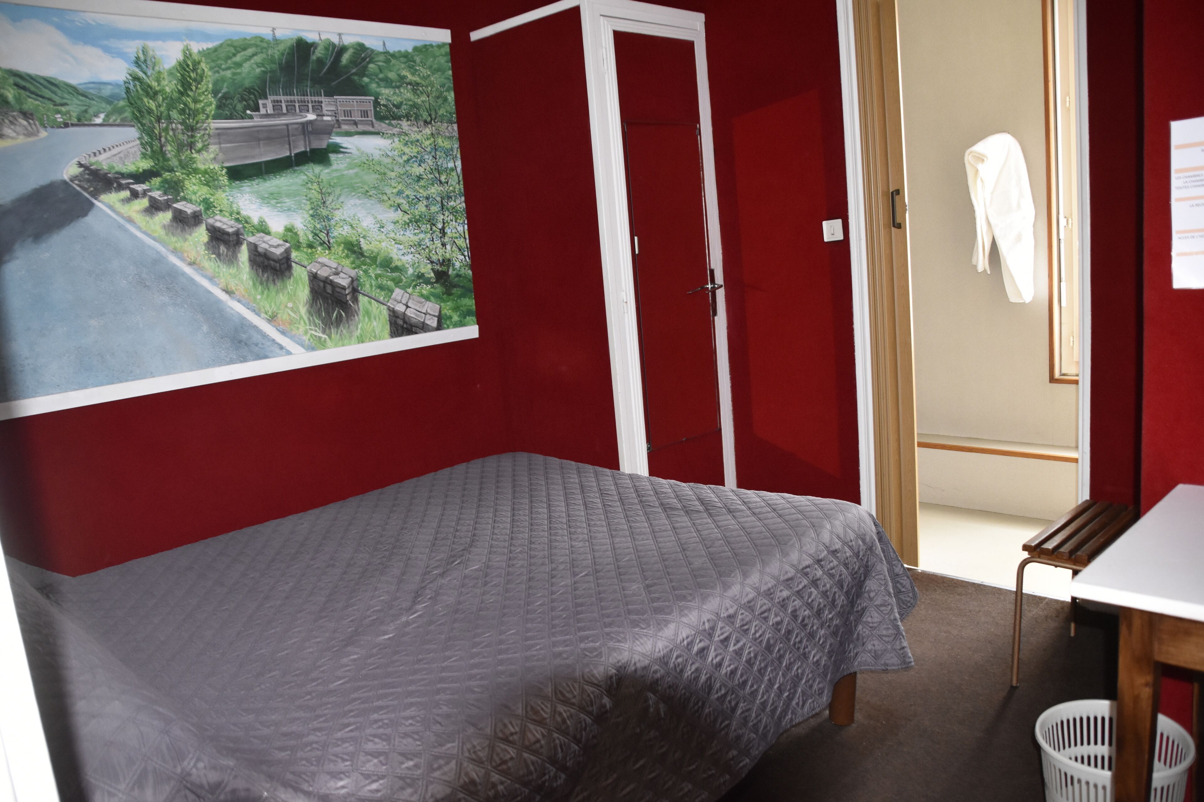 A room with a bed, a desk, and a red wall.