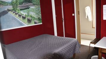 A room with a bed, a desk, and a red wall.