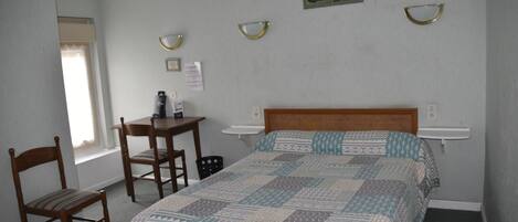 A bedroom with a bed, a desk, two chairs, and a small table.