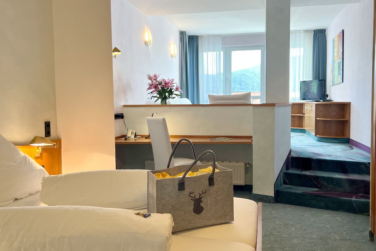 A hotel room with a bed, a desk, a chair, a TV, and a staircase.