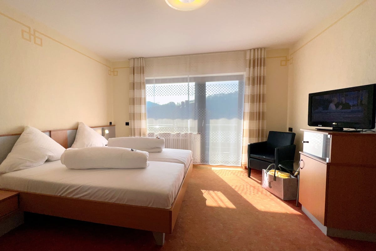 A hotel room with two beds, a TV, a chair, and a desk.