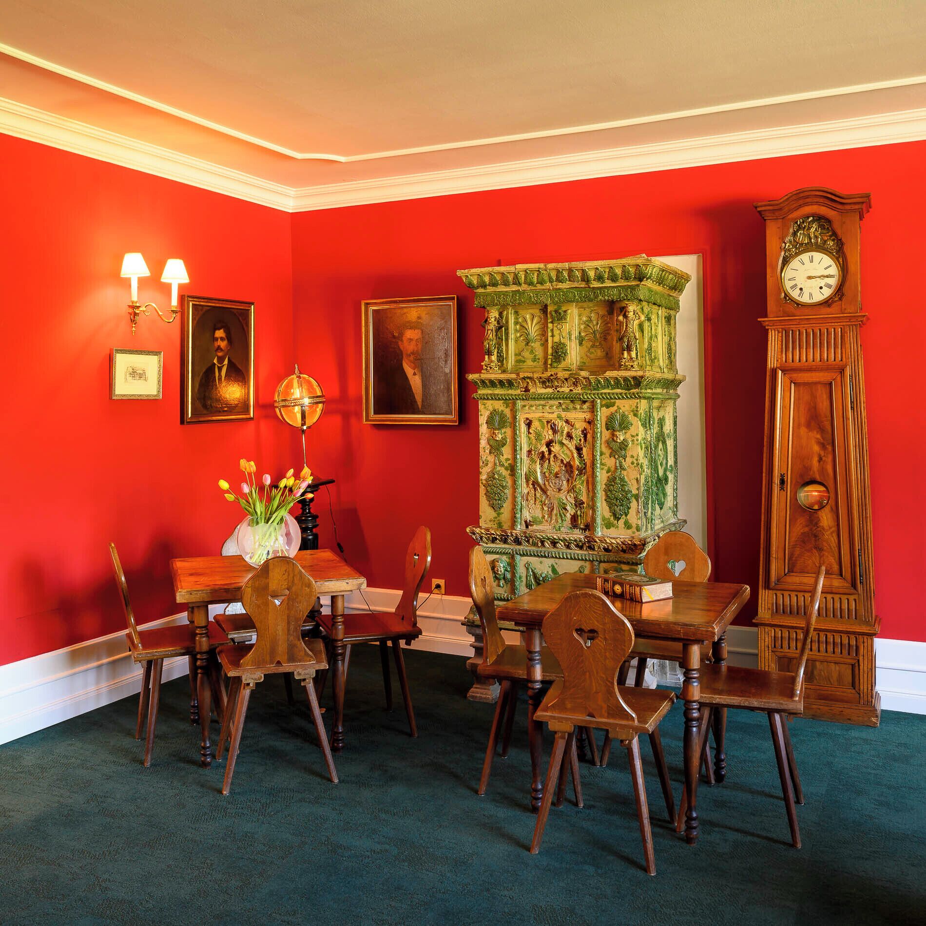 A dining room with a red wall, a green cabinet, and a wooden clock.