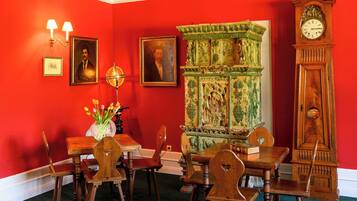 A dining room with a red wall, a green cabinet, and a wooden clock.
