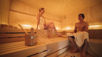 A sauna with wooden benches and benches, a wooden bucket, and a towel.