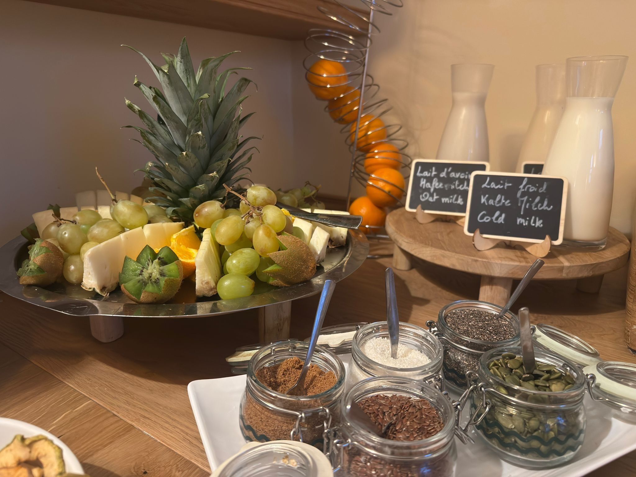 Um buffet de café da manhã com diversas frutas, queijos e opções de leite.