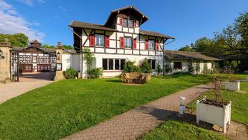 A traditional two-story building with a symmetrical facade, a paved entrance, and a well-maintained lawn.
