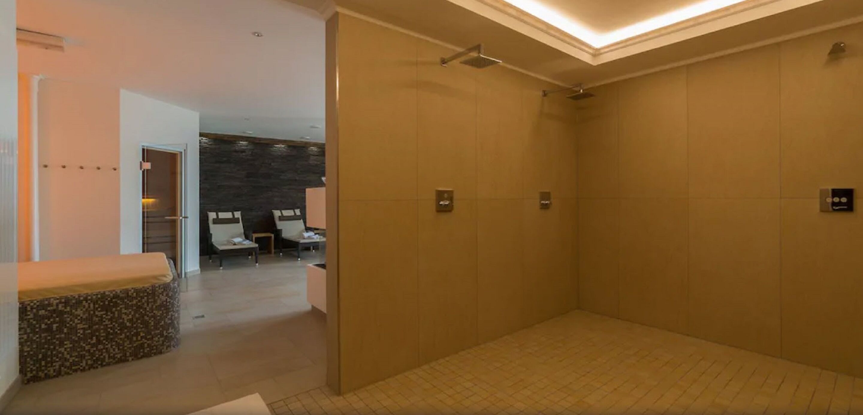 Un baño moderno con ducha a ras de suelo, un banco y una zona de estar con vistas a la piscina.