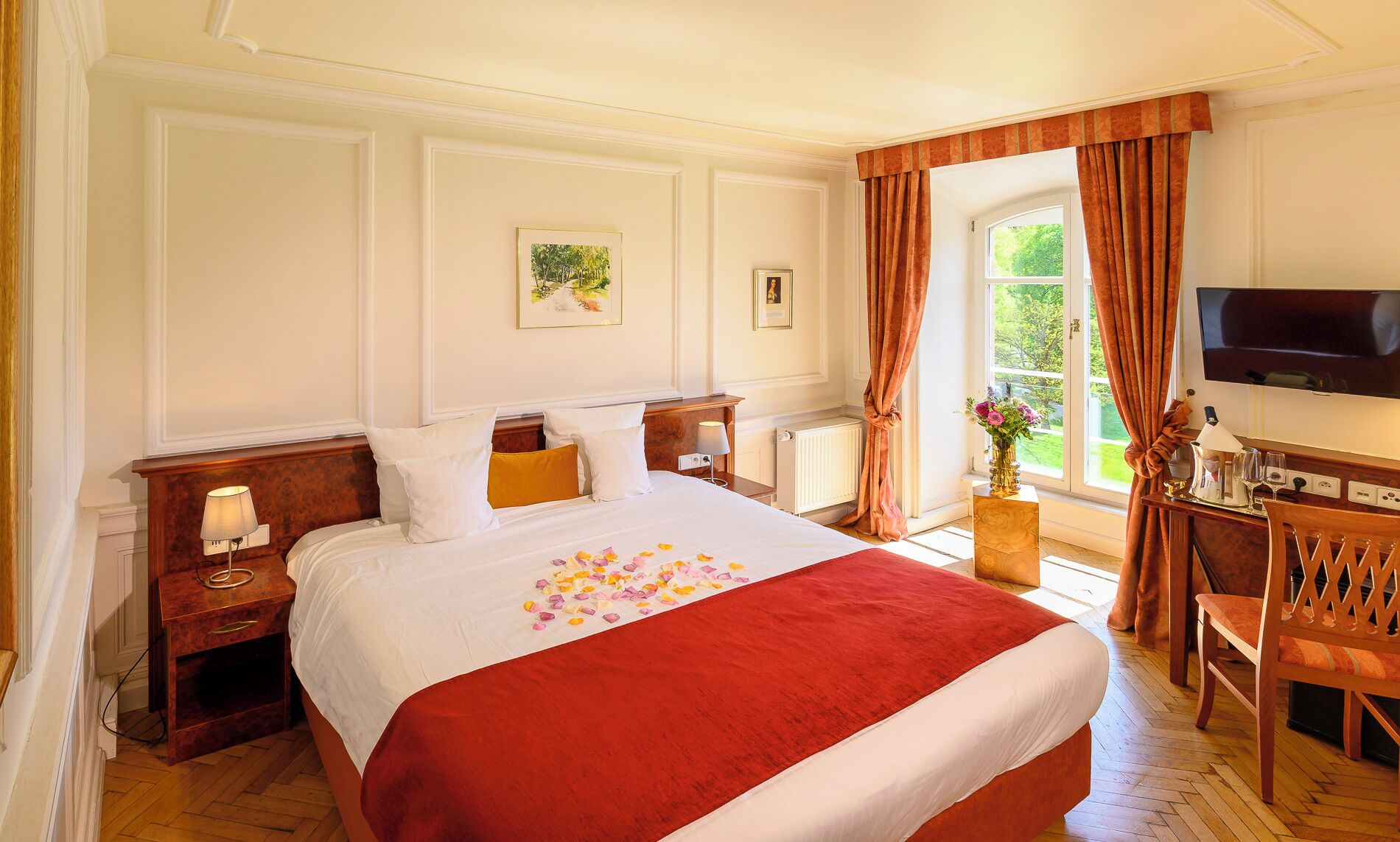 Una habitación de hotel con una cama grande, un escritorio con televisor y una ventana con cortinas.