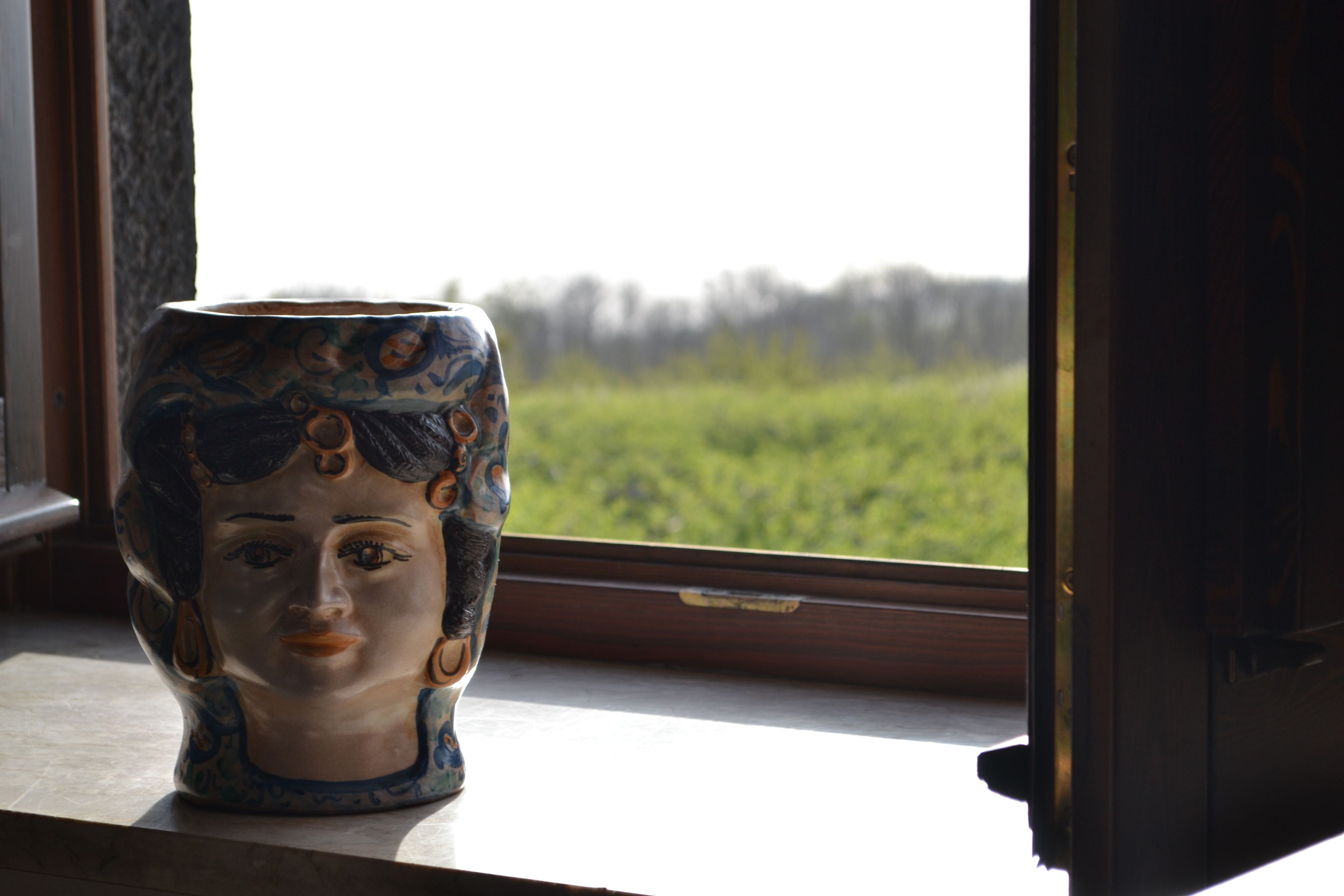 Eine Keramikvase mit floralem Muster auf einem Fensterbrett.
