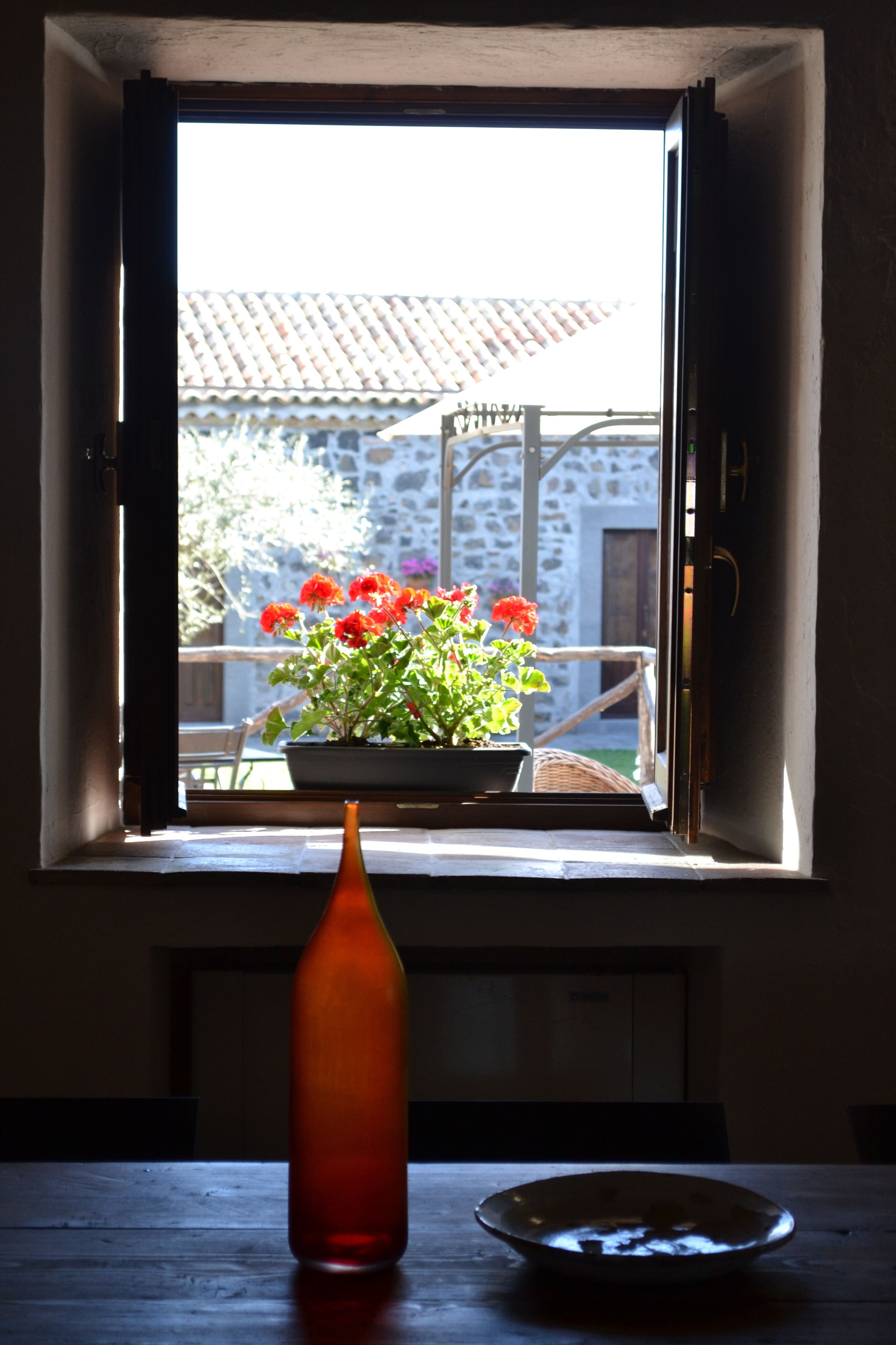 A window with a potted plant and a vase on a table.