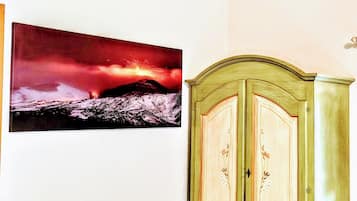 A room with a green cabinet and a framed picture of a volcanic landscape.