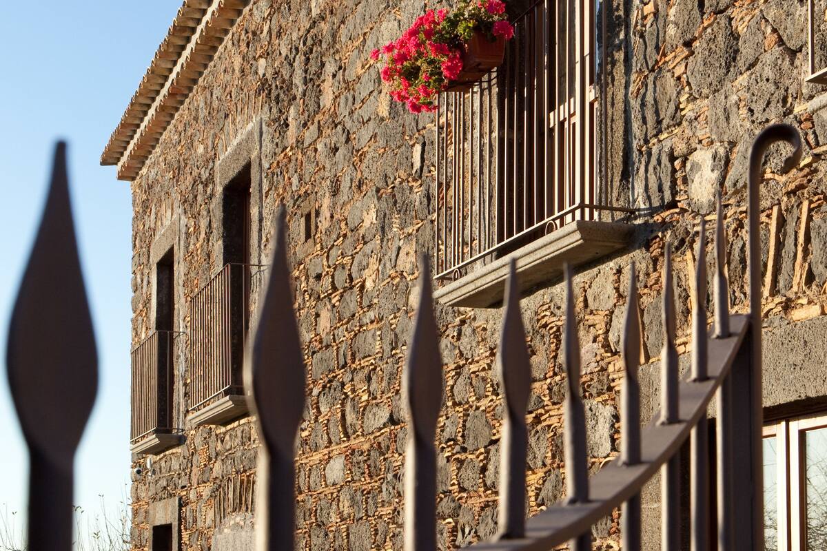 A stone building with a balcony featuring a flower pot.