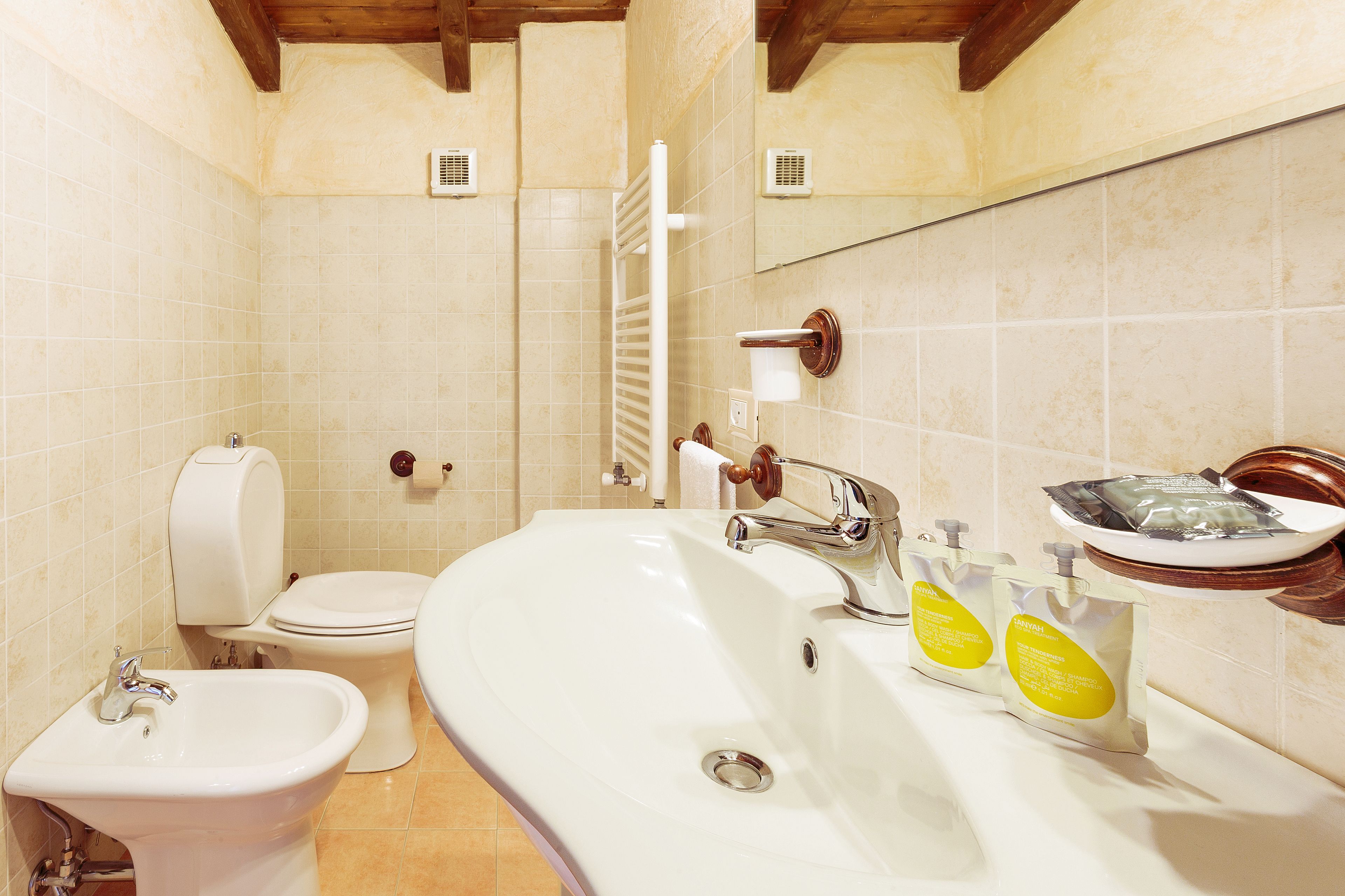 Un baño con bidé, inodoro, lavabo y espejo.