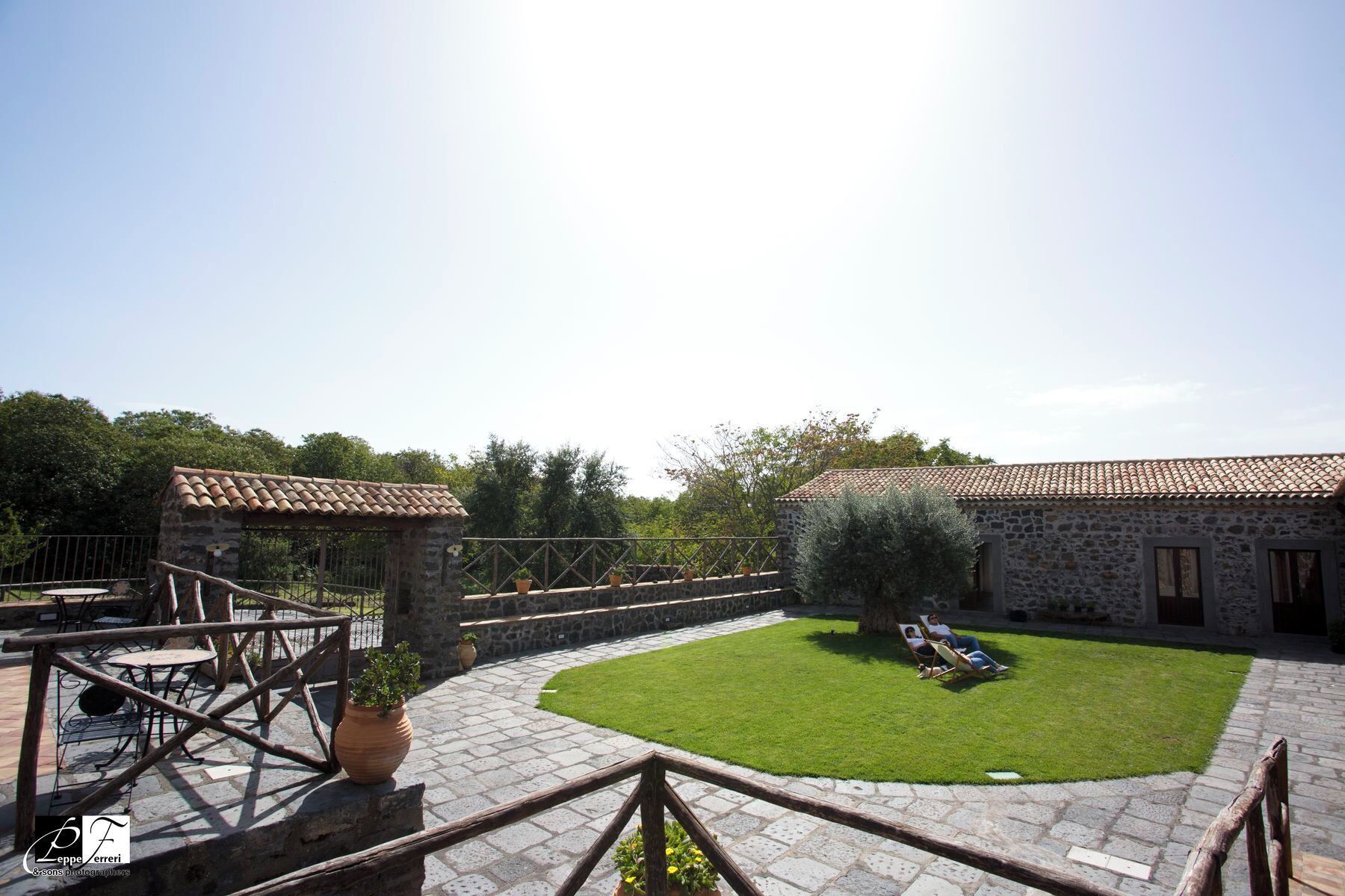 Un patio con un edificio de piedra, un pequeño jardín y mobiliario para exteriores.