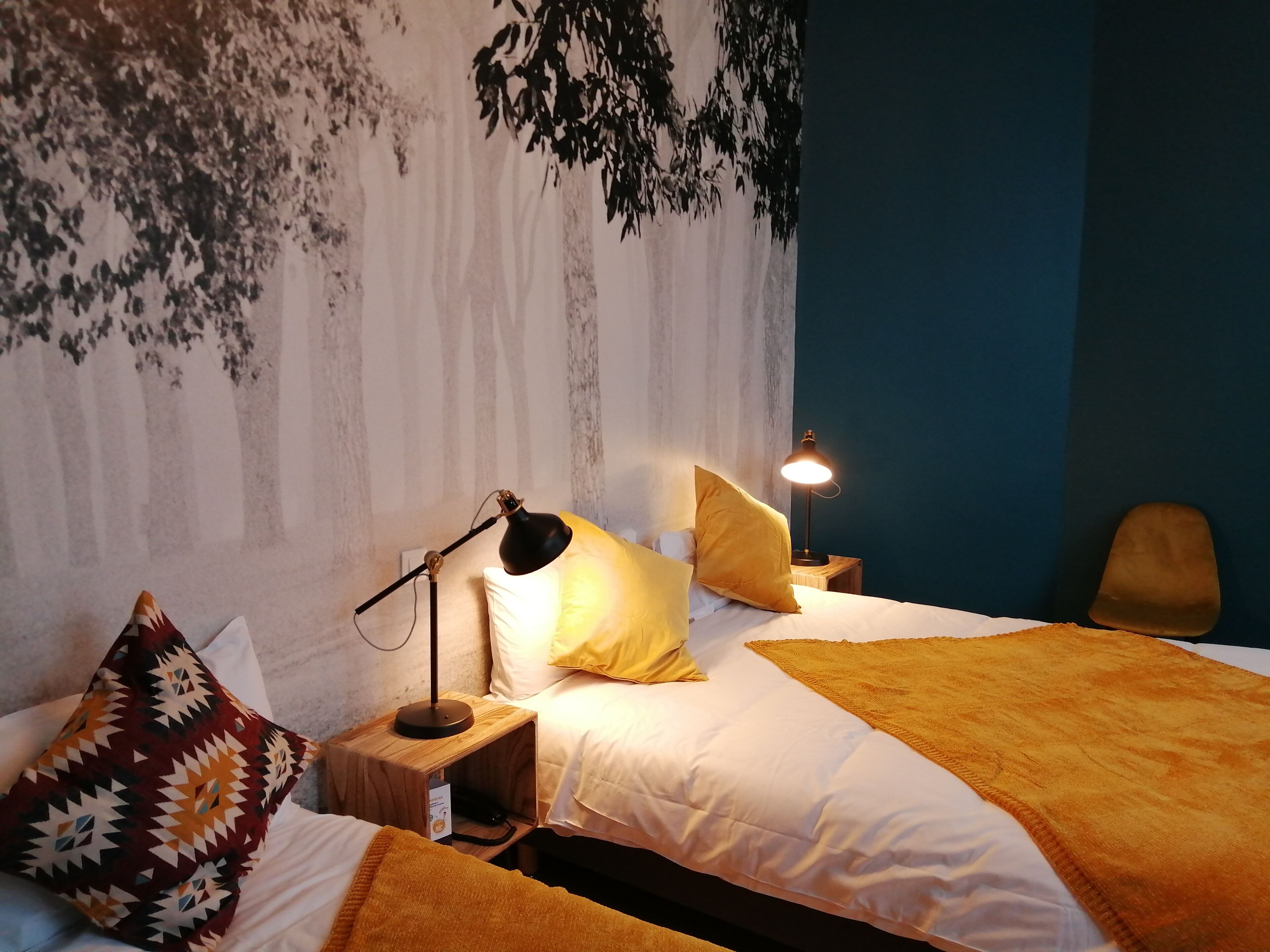A neatly made bed with white linens, a patterned throw blanket, and two lamps on wooden side tables.