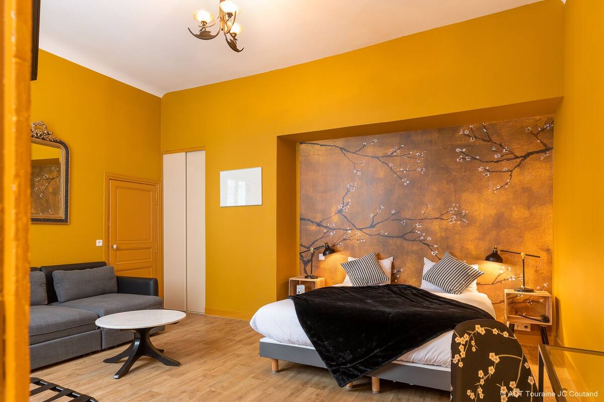 A modern bedroom with a bed, bedside tables, a sofa, and a round table.