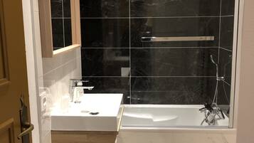 Un baño moderno con bañera, ducha y tocador con espejo.