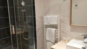 Un baño moderno con ducha de vidrio, lavabo blanco y un perchero para toallas.