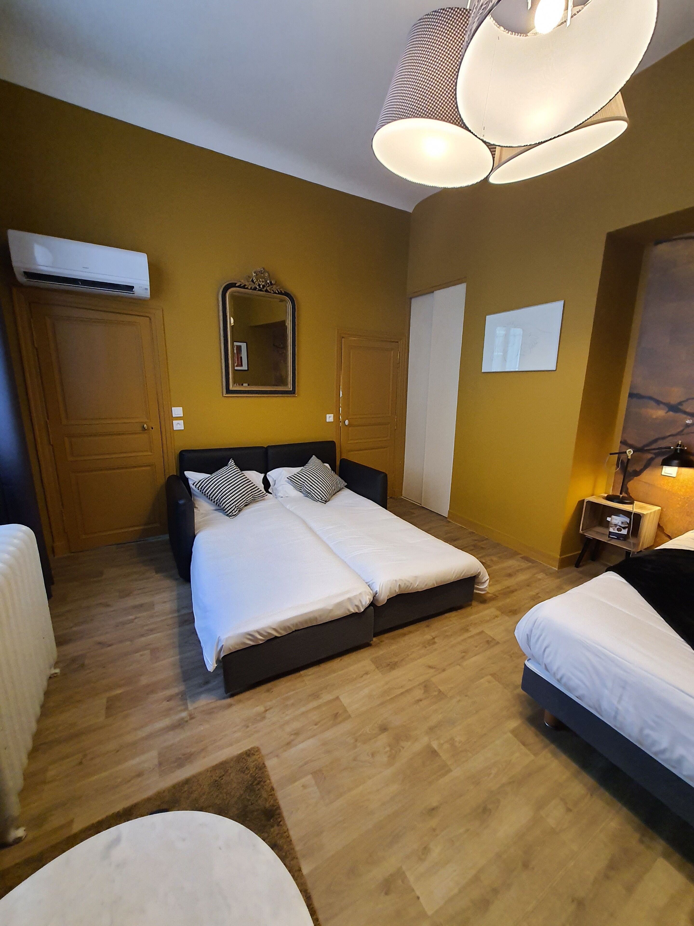 Une chambre avec un lit double, une table de chevet, un miroir et un appareil de climatisation.