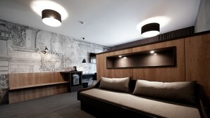 A modern living room with a sofa, a coffee table, and a wall-mounted TV. - Hôtel Nota Bene (Montceau-les-Mines)